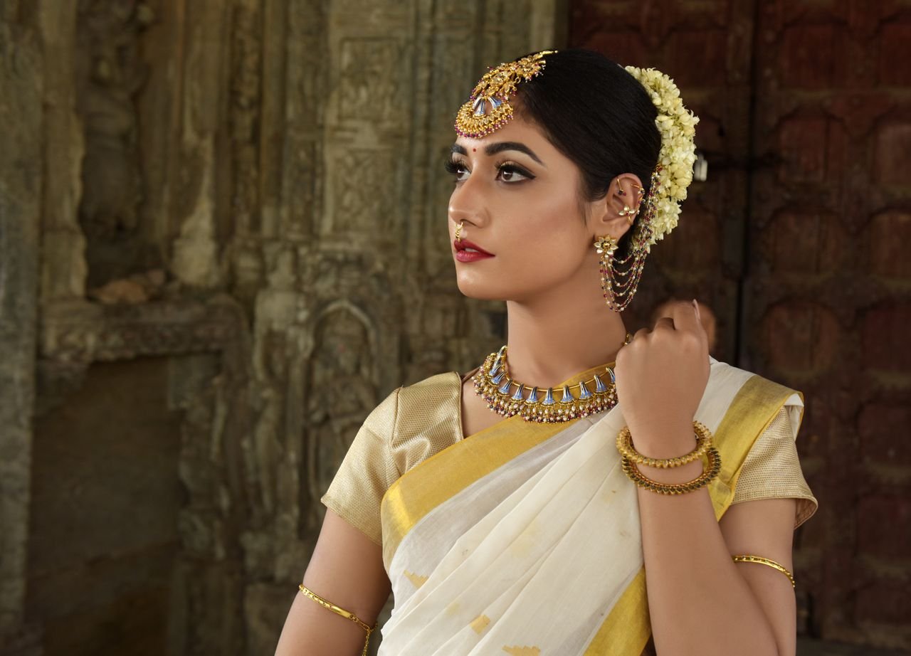 collection-01 Beautiful Indian woman in traditional saree, adorned with exquisite jewelry, set against historic architecture.