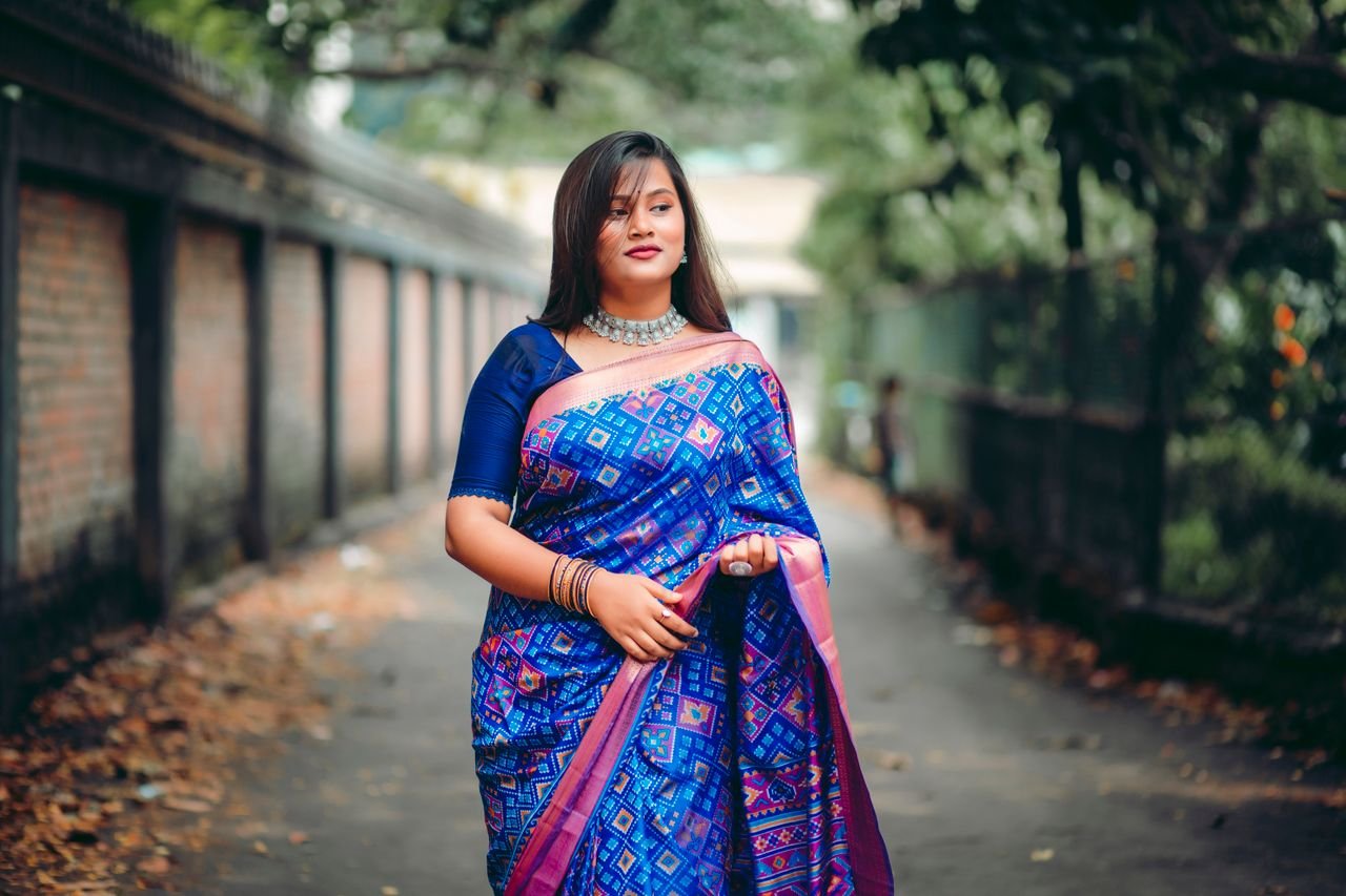summer-sale A South Asian woman in a vibrant blue saree walks outdoors in Dhaka, Bangladesh.