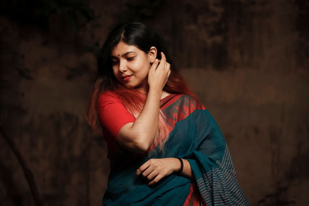 collection-03 Elegant portrait of a woman wearing a traditional saree in a relaxed pose, showcasing cultural fashion.